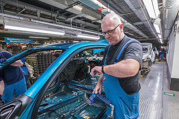 Mitarbeiter in der Produktion von Autohersteller BMW schaut auf den Fitnesstracker an seinem linken Handgelenk